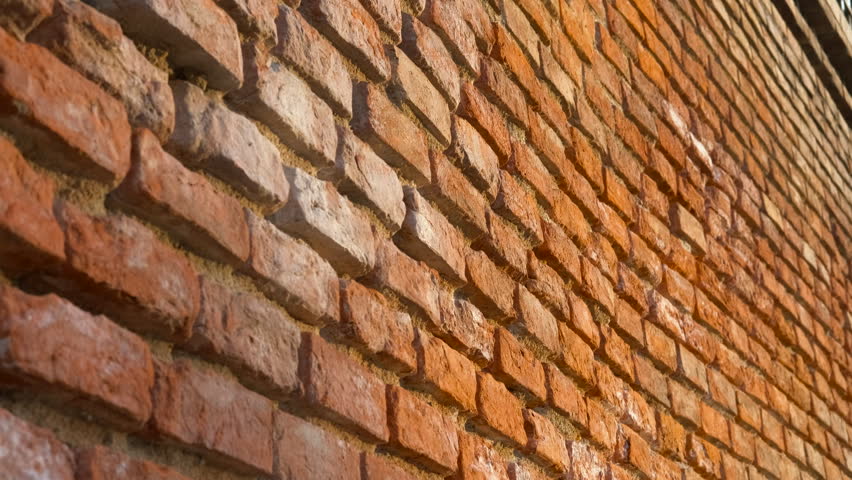 Brick wall moving closer revealing texture. Brick wall moves closer, showcasing intricate textures and details. Sunlight casts shadows across the bricks, enhancing the visual depth