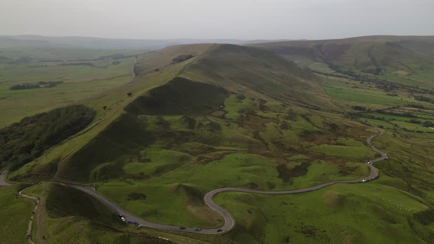 Aerial view of Mam Tor hill with its winding road and lush green slopes in the Peak District, Hope Valley, England, United Kingdom.