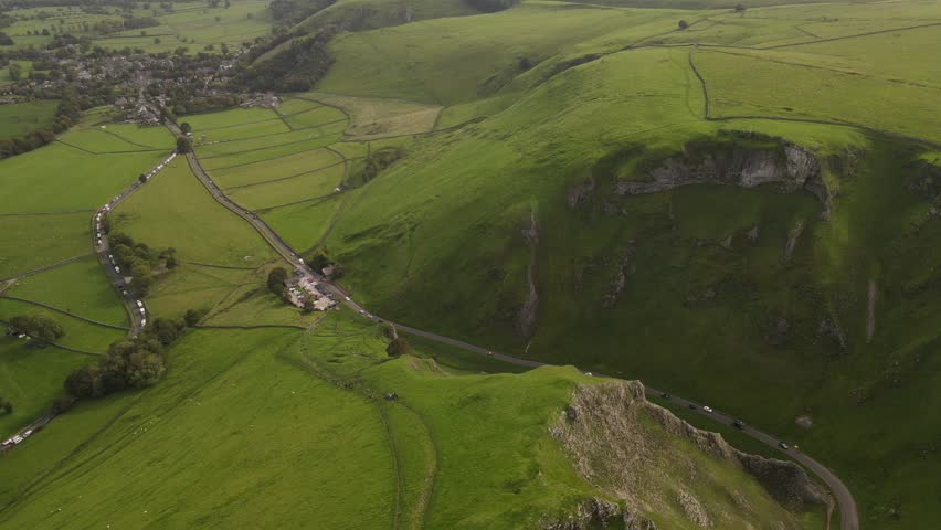 Aerial view of the winding road through the limestone cliffs of Winnats Pass in the green hills of Hope Valley, England, United Kingdom.