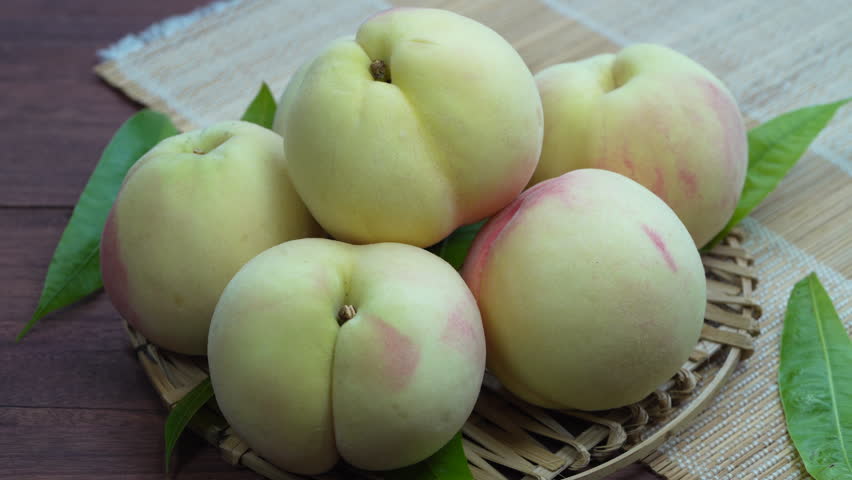 White Peaches with leaves on the wooden table, Fresh White Peach on wooden basket in wooden Background.