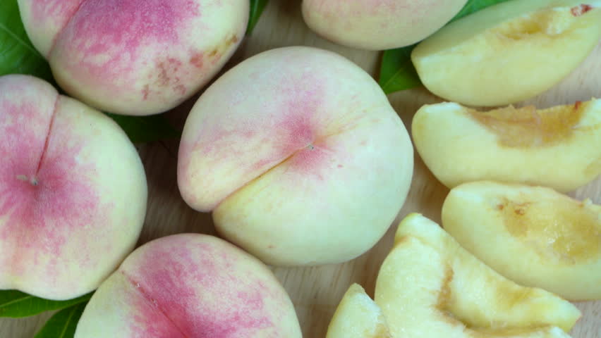 White Peaches with leaves on the wooden table, Fresh White Peach on wooden basket in wooden Background.