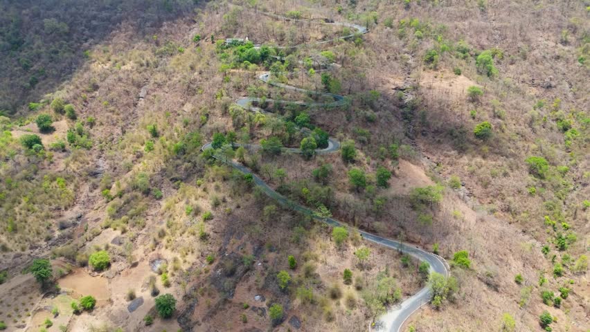 Beautiful drone view of  Wilson Hills located in Gujarat-India, A high-resolution aerial drone photograph of a winding mountain road featuring multiple hairpin bends through a dry deciduous forest