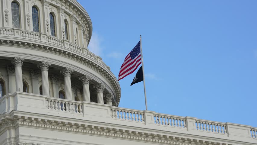 Capitol with American flag waving. . Congress and Senate chambers. Congress under the Capitol roof. Congress as American symbol. Congress in the United States Capitol.