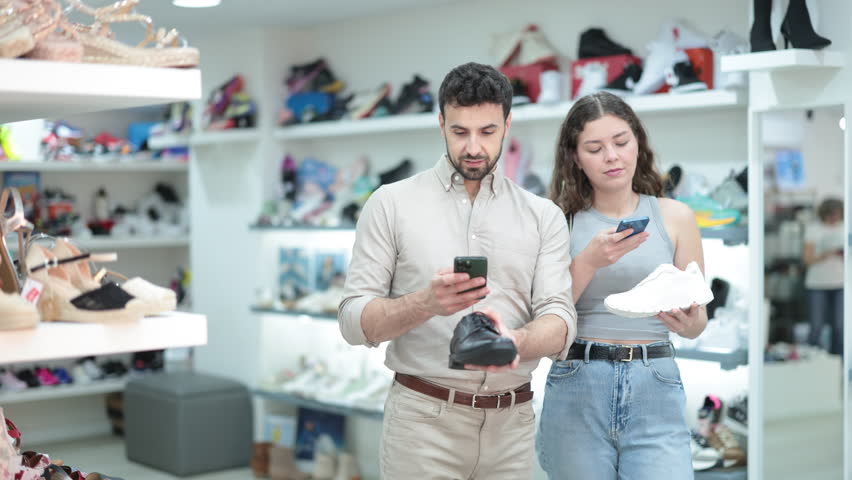 Married couple scans QR codes on the labels of various shoes together in a shoe store. High quality 4k footage