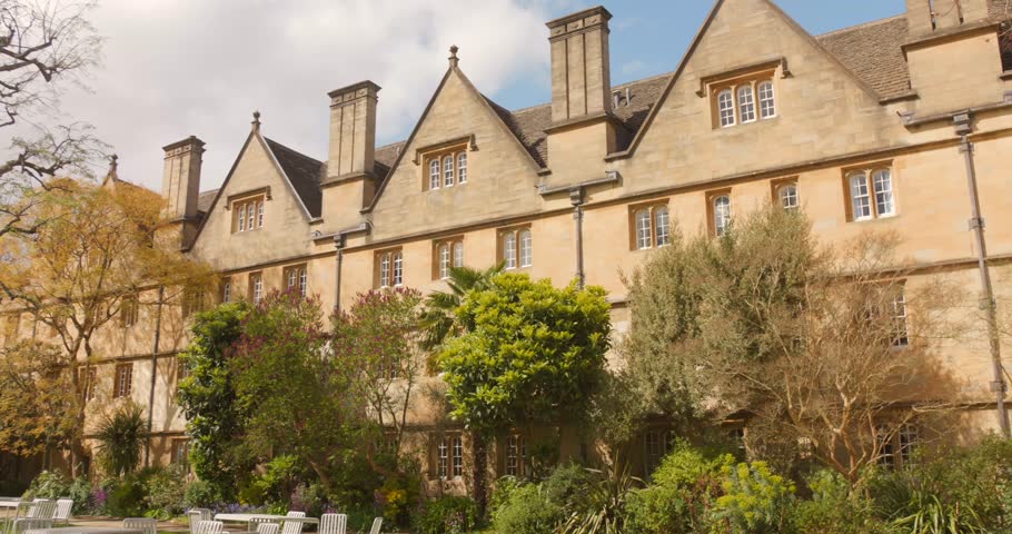 Historic Wadham College building with garden and outdoor seating on a sunny day