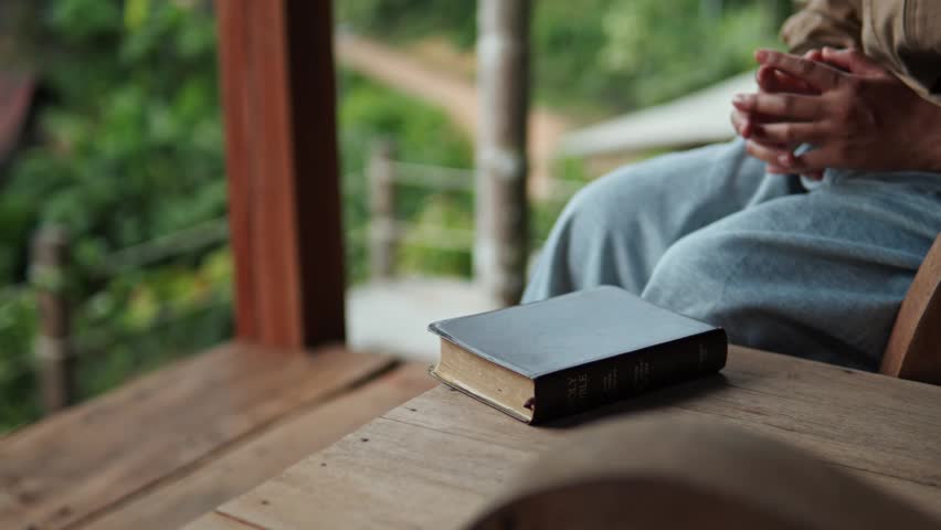 A young woman sits praying to God with her Bible, asking for a peaceful healing in her life healed by love and His holy word