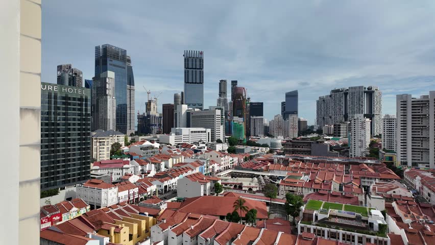 aerial-style panoramic view overlooking Singapore’s Chinatown district, featuring iconic red-roofed heritage shophouses contrasted against a dramatic skyline of modern skyscrapers under a bright, clou
