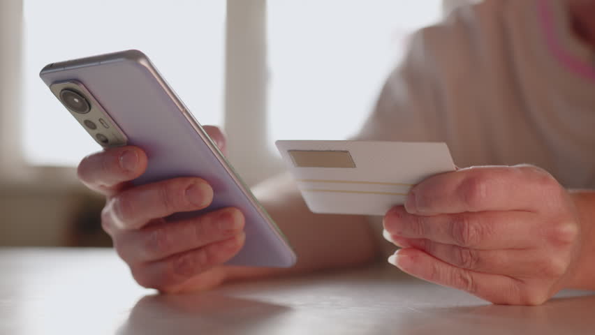Woman using smartphone and bank card for online shopping