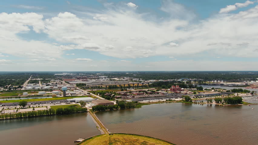An establishing aerial shot showcasing the industrial landscape and urban development along the Green Bay waterfront under a bright blue sky.