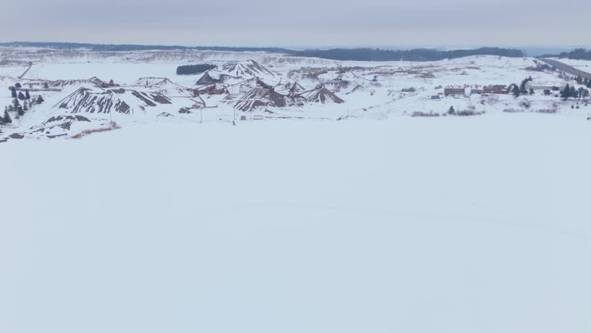 Snowy Caledon aggregate site with conveyor machinery stretching across sand piles in winter.