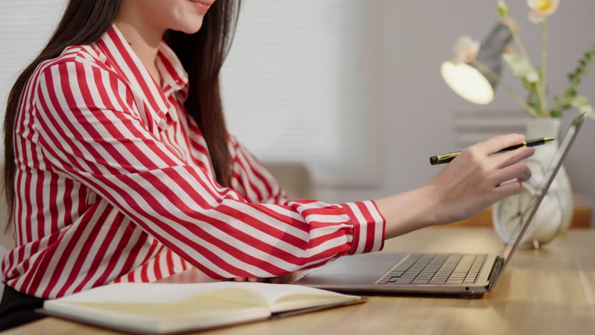Woman working with a notebook and laptop at a desk, ideal for note taking, planning, productivity, study, office work, home office and professional lifestyle concepts.
