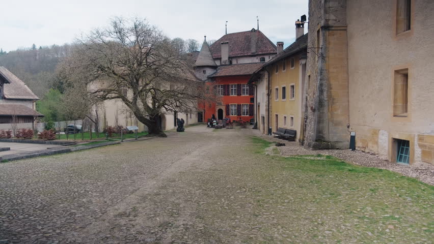 Push in shot of Romainmotier Priory courtyard, former Cluniac priory, during the day in canton of Vaud, Switzerland, wide shot