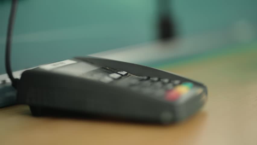 Close up of a female hand holding a credit card and making a contactless payment on a POS terminal, symbolizing the ease and speed of modern electronic transactions and cashless shopping