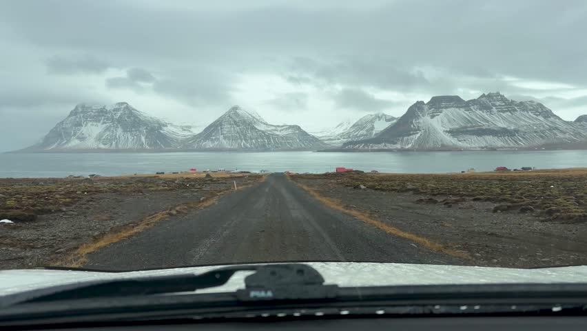 Car Driving Through Unpaved Road Leading Toward The Fjord With Snowy Mountains In Gjogur, Iceland. - POV shot