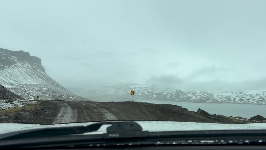 Car POV Driving On A Narrow Winding Road By The Mountain During Snowfall In Winter.