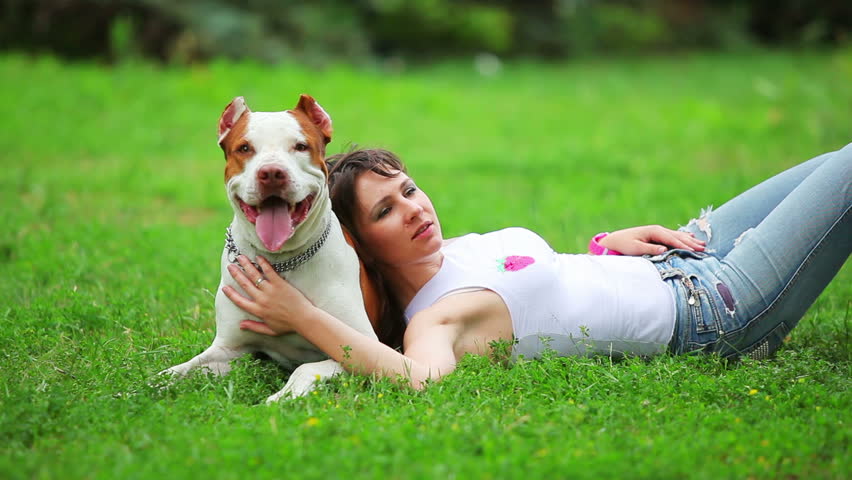 Woman with her beautiful dog playing outdoors, pit bull terrier