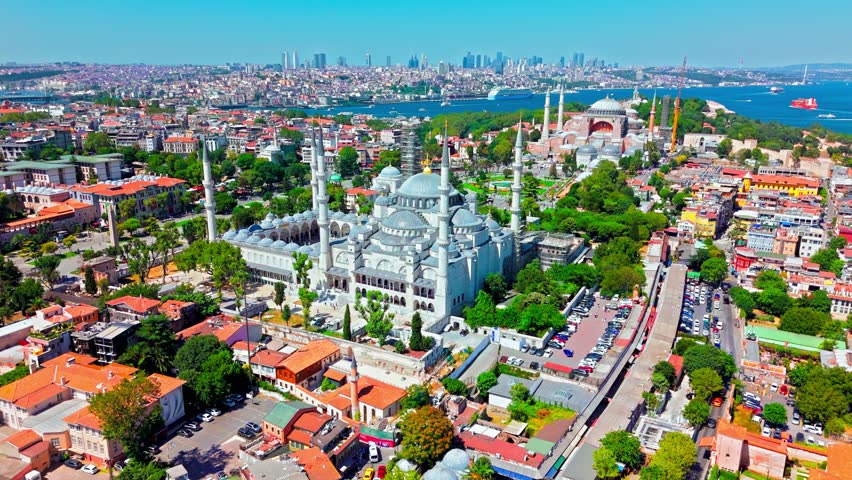 Aerial view of the Blue Mosque in Istanbul, Turkey. The Sultan Ahmed Mosque stands with its domes and minarets near Hagia Sophia, green parks, the Bosphorus and the modern city skyline.