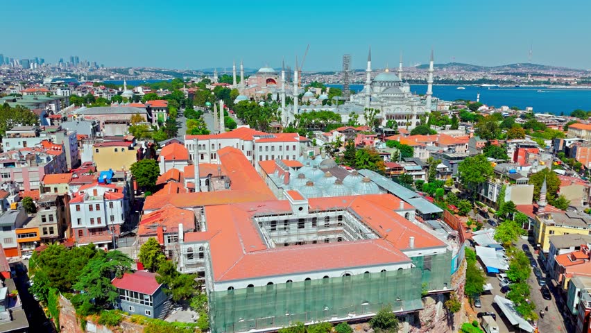 Drone view of Sultanahmet district in Istanbul, Turkey. Hagia Sophia Grand Mosque stands near red rooftops, gardens and historic city buildings.