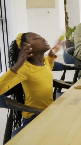 Vertical video: Raising hands girl in yellow top turning to adult offering bowl of lemons at table. Child, family, mother, sunlit, home, contemporary, vertical video