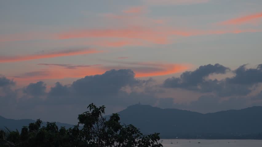 Warm hues of orange and pink light the twilight sky over a peaceful lake.