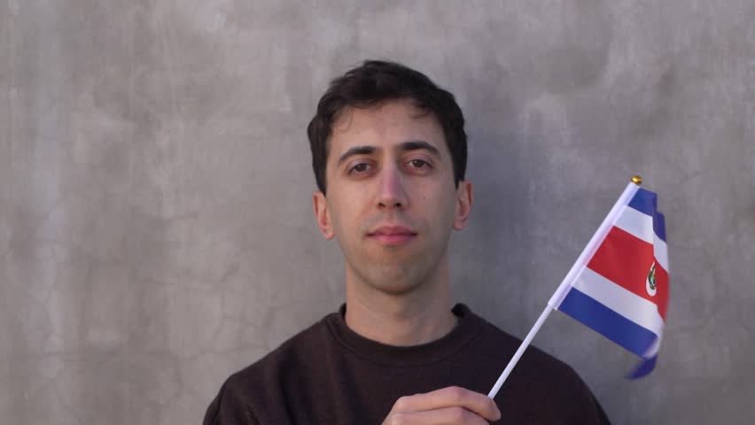 Male adult waving Costa Rica country flag. Slow motion. Close up.