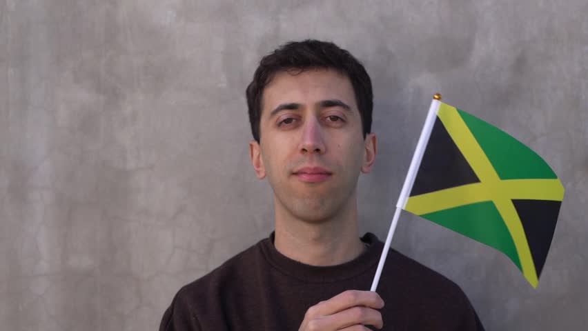Person waving the Jamaican flag in slow motion. Close up shot.