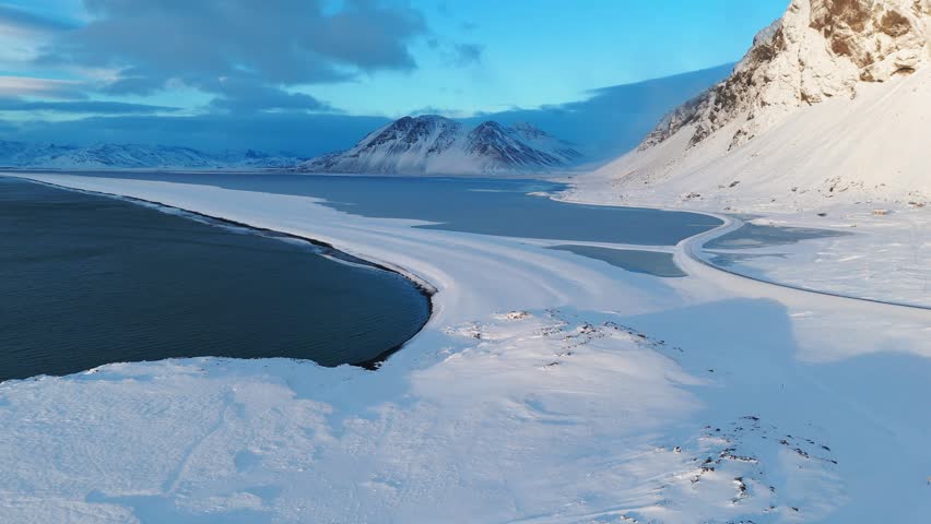 Aerial view of snowy mountains and frozen coast in East Iceland