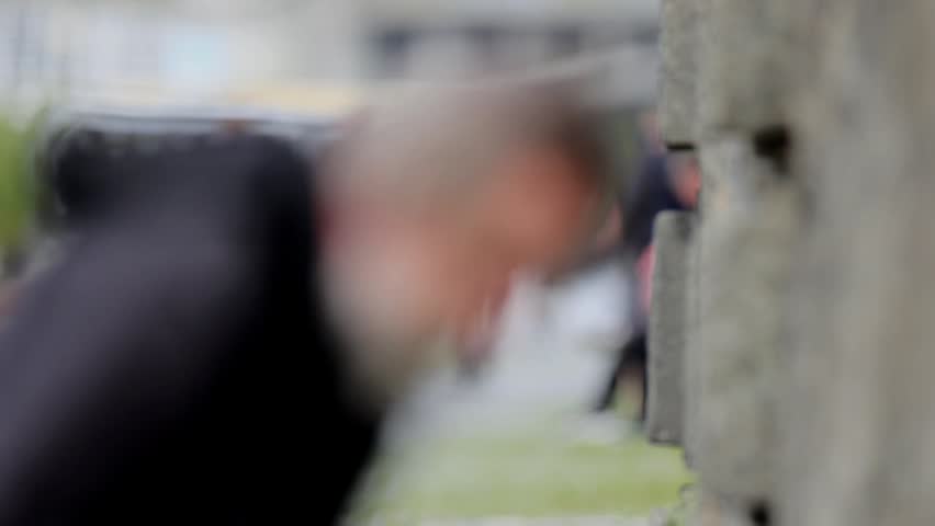 Elderly homeless man searching for something in garbage bin and on city street