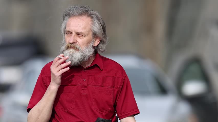 Elderly homeless man searching for something in garbage bin and on city street