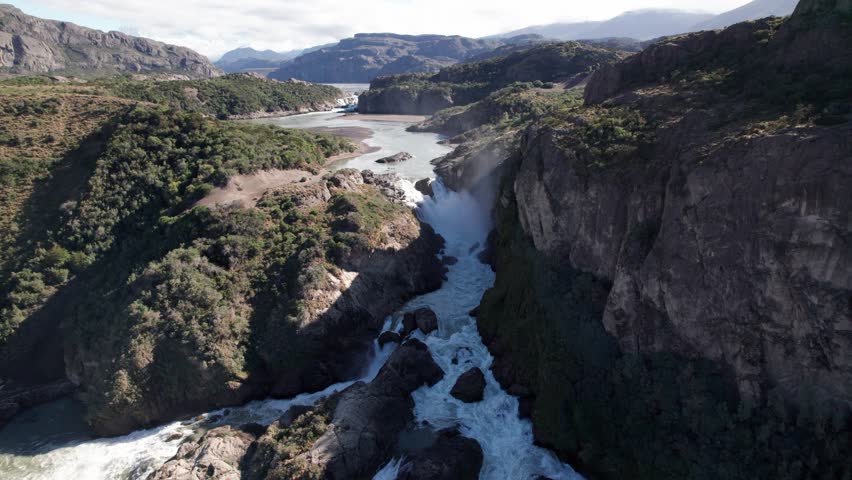 Aerial View of Majestic Waterfall Flowing Through Rugged Mountain Canyon