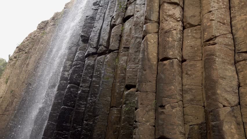 Twin waterfalls cascading through towering basalt rock formation in scenic natural park. Dramatic landscape featuring flowing water, rugged cliffs and geological beauty in Mexico.