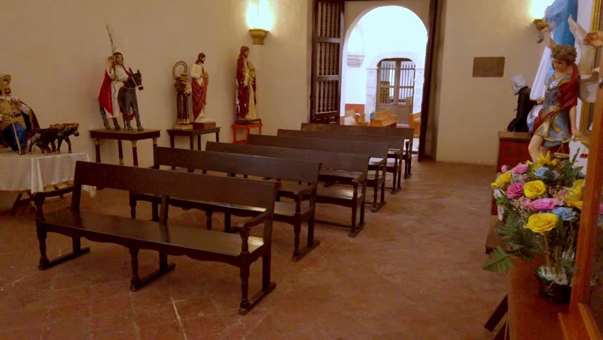 Historic church interior featuring wooden benches, religious statues and peaceful chapel setting. Sacred Christian architecture with devotional artwork and welcoming spiritual atmosphere.