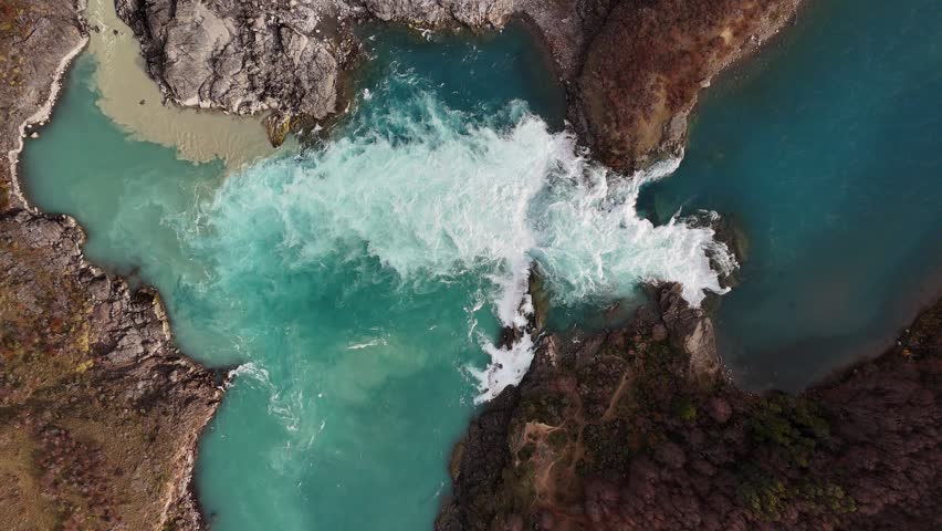 Aerial view of Baker River waterfall in Chilean Patagonia. Turquoise glacial waters cascading over rocks surrounded by native forest. Drone footage of one of Chile