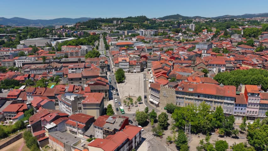 Aerial - Guimaraes cityscape with red rooftops a central square and green hills beyond