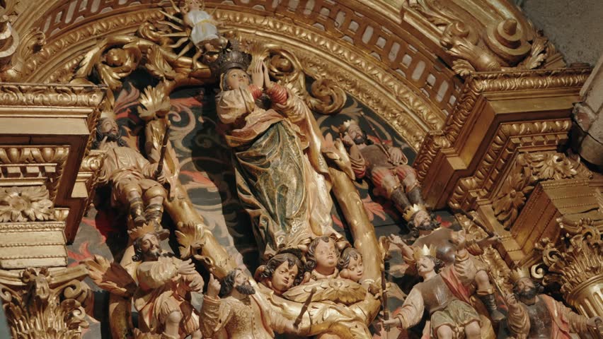 Painted wood sculptures of crowned figure surrounded by angels and saints in gilded retable