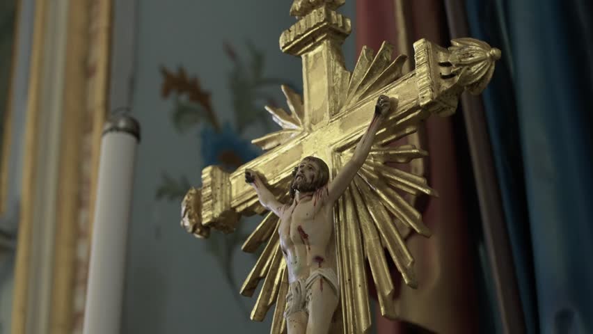 Carved crucifix of Jesus Christ on a golden cross with radiant sunburst rays on a church altar