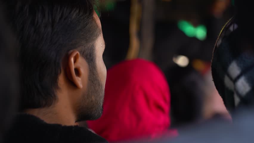 A man wearing a black shirt and a red headscarf is seen in a crowd, with others blurred in the background, Chakrata, Dehradun, Uttarakhand.