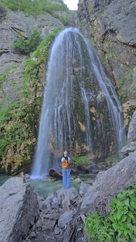 Albania welcomes travelers to Theth, showcasing magnificent waterfalls and lush nature. A woman experience a refreshing escape, perfect for adventure and relaxation in this hidden gem of tourism.