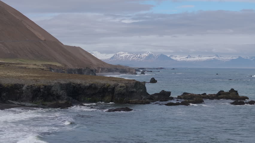 Rugged coastal coves, black sand beaches, snowy mountaintops in Iceland. Aerial