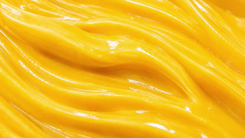 Video 4K Glossy Mango Juice Wave Texture Background, Smooth Flowing Tropical Fruit Liquid with Vibrant Yellow Surface for Food Advertising and Motion Graphics