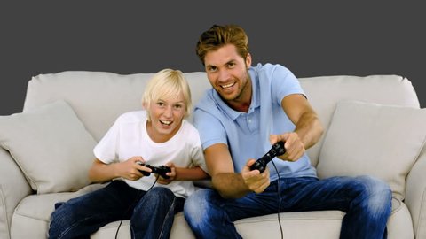 Father and son playing video games on grey background in slow motion