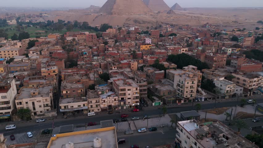 Aerial view of Giza pyramids towering over a crowded city.