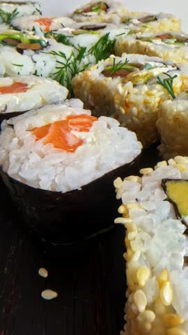 A variety of sushi rolls featuring fresh ingredients like salmon and avocado, displayed on a wooden board.