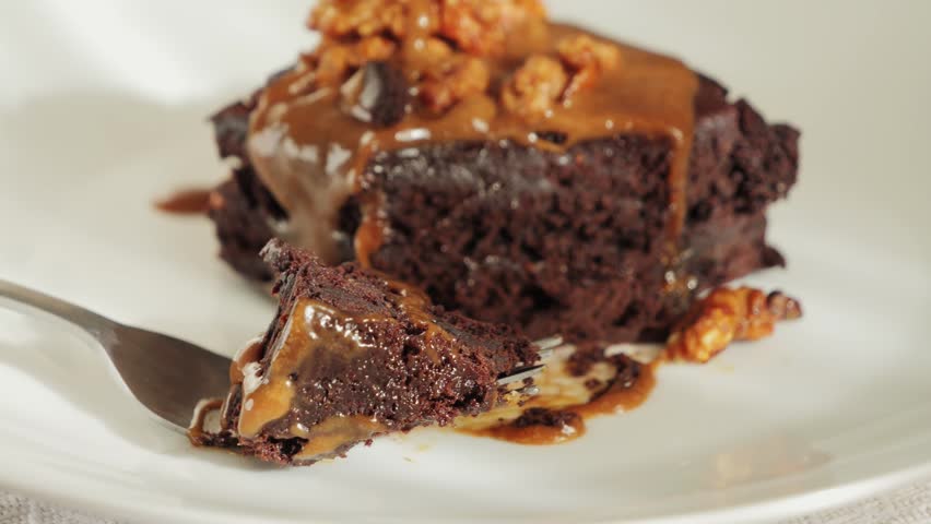 Chocolate cake with nuts and salted caramel. Delicious piece of cake brownie on a plate. High quality 4k footage