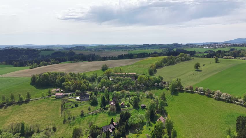 Aerial view cultivated fields and patchwork meadows, country lanes, scattered farmsteads and spring planting
