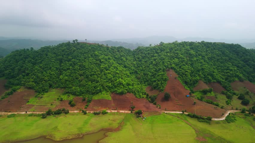 Scenic Aerial View of Monsoon Hilly Jungle with Dense Green Forest, Mist Covered Mountains, Rainy Weather, Lush Vegetation, Cloudy Sky, Natural Wilderness and Beautiful Tropical Landscape Scenery