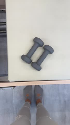 Two grey small dumbbells lie on a light soft surface.