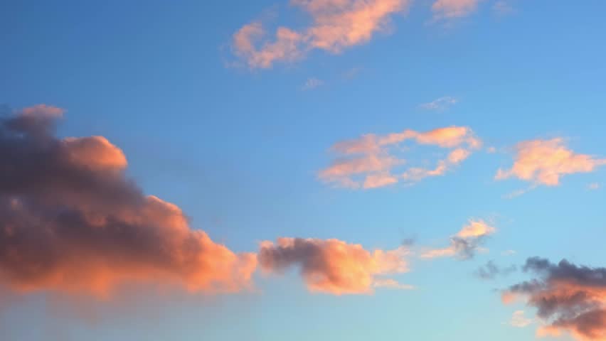 Pink and orange clouds float in a blue sky during sunset. evening sky, sunset colors, nature background. Beautiful skyscape. Golden hour cloudscape. High quality 4k footage.