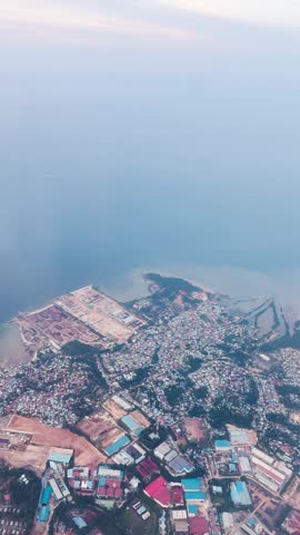 4K vertical view of Batam Island and ocean as seen from moving airplane window. Scenic aerial view of Batam island near Singapore. Travel concept.