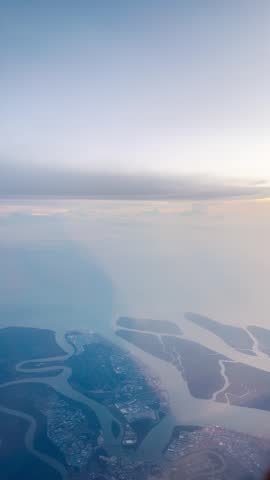 4K vertical video of ocean and Port Klang as seen from flying airplane near Kuala Lumpur, Malaysia. Aerial view of landscape seen during air travel. Travel, transportation and holidays concept. 